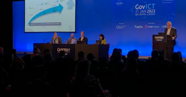 photo of four panelists and a presenter at the GovNet conference - blue blackdrop and screen with graph demonstrating rise in Cloud use.