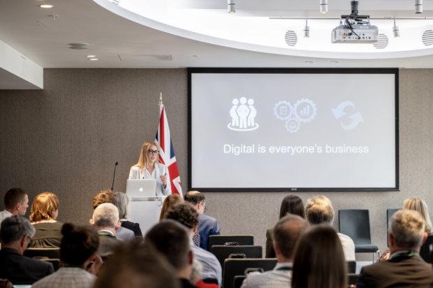 Photo of Megan Lee presenting at Digital Strategy Launch, on the screen 'Digital is everyone's business'.