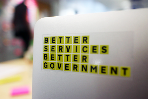  An open laptop with a sticker saying 'Better services better government'
