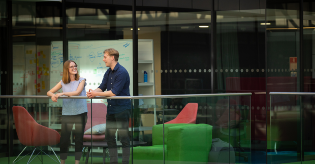 Photo of two colleagues in discussion over balcony in office