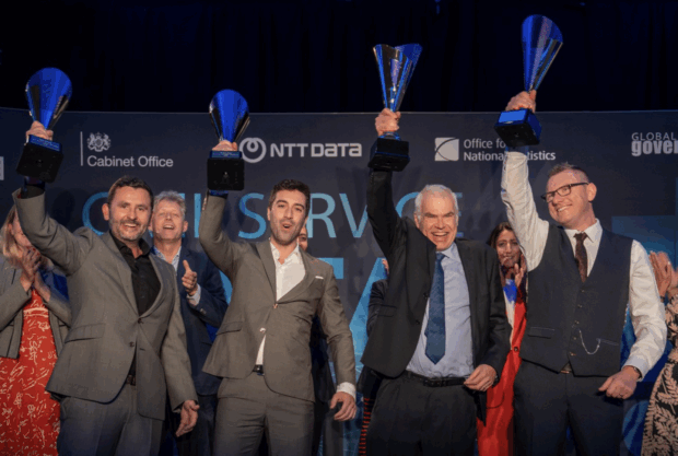 A group of people celebrating with a trophy in each hand from the Civil Service Data Challenge 2024